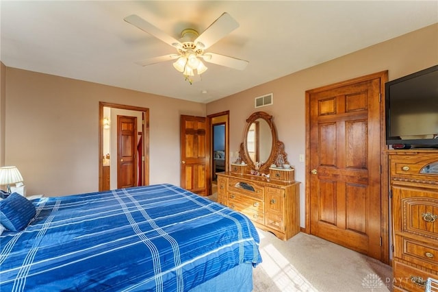 carpeted bedroom with ensuite bath and ceiling fan