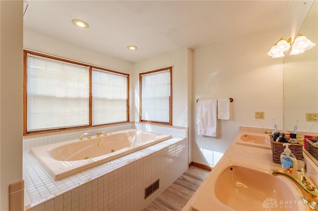 bathroom with hardwood / wood-style flooring, vanity, and tiled tub