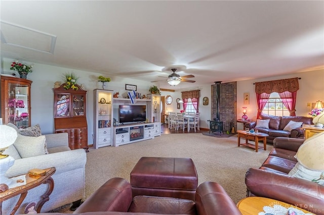 living room with carpet flooring, ceiling fan, and a wood stove