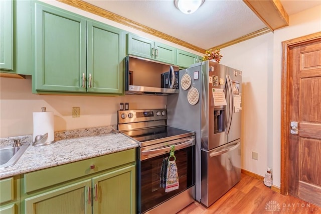 kitchen with ornamental molding, green cabinets, light stone counters, stainless steel appliances, and light wood-type flooring