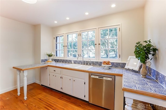 kitchen with sink, tile countertops, light hardwood / wood-style flooring, dishwasher, and white cabinets