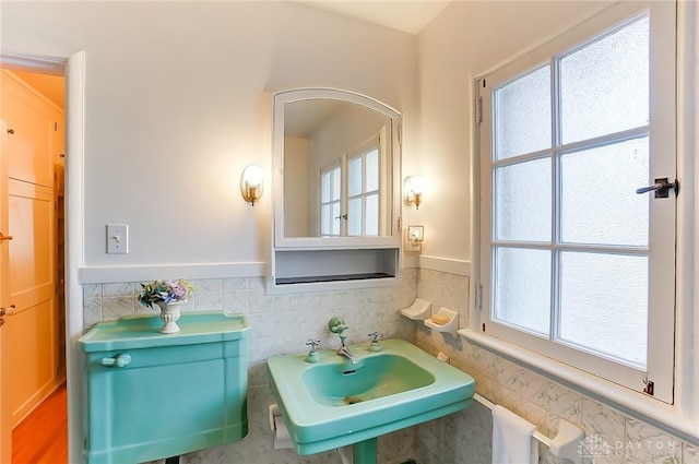 bathroom with sink, a wealth of natural light, and tile walls