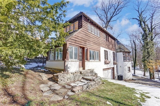 view of property exterior with a garage and central AC unit