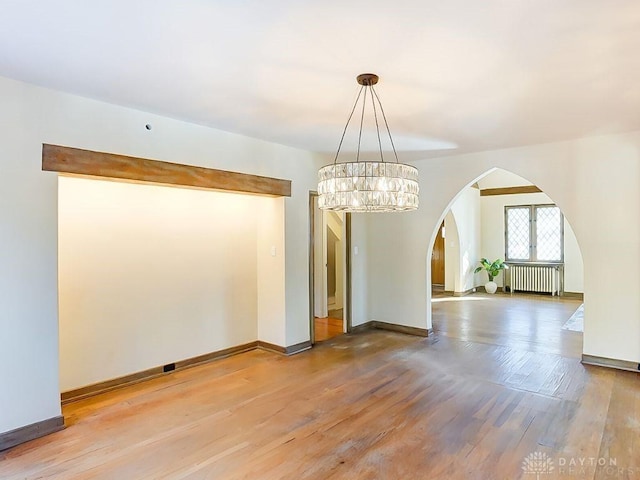 unfurnished dining area featuring hardwood / wood-style flooring, radiator, and an inviting chandelier