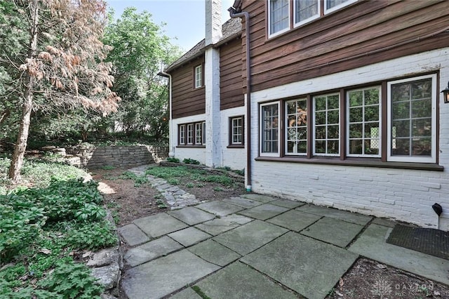 1515 Woodstock Dr, Oakwood, OH 45419 - view of home's exterior with brick siding, a patio area, and a chimney