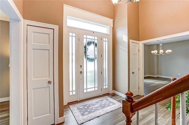 entrance foyer with a notable chandelier, a towering ceiling, and hardwood / wood-style flooring