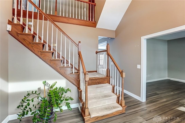 stairway with hardwood / wood-style floors and a high ceiling