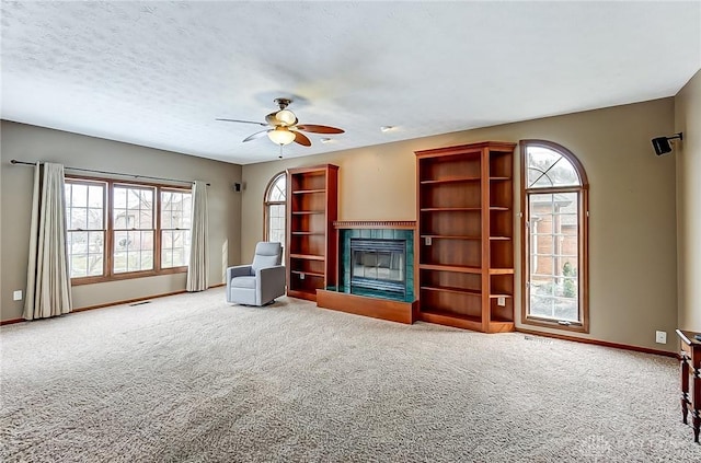 unfurnished living room featuring ceiling fan, carpet floors, and a textured ceiling