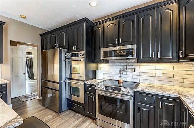 kitchen featuring light stone countertops, decorative backsplash, light hardwood / wood-style flooring, and stainless steel appliances