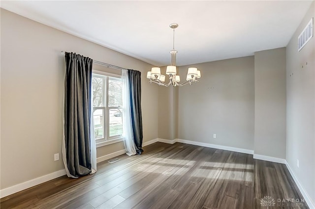 unfurnished room featuring dark wood-type flooring and a notable chandelier