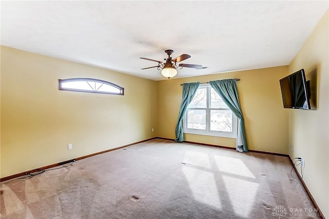 empty room featuring ceiling fan, light colored carpet, and a healthy amount of sunlight