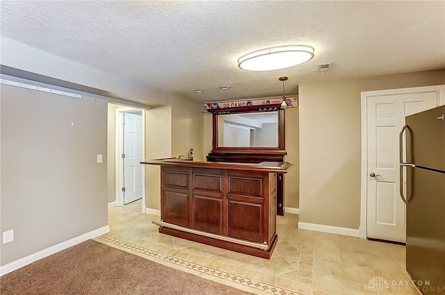 kitchen featuring black fridge, decorative light fixtures, and a textured ceiling