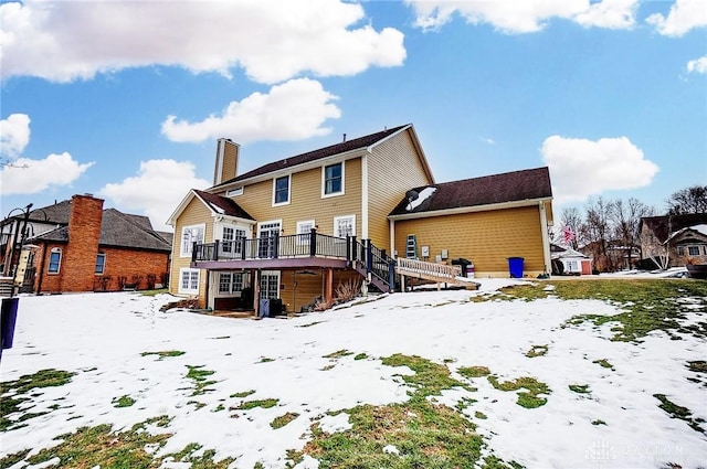 snow covered house featuring a wooden deck