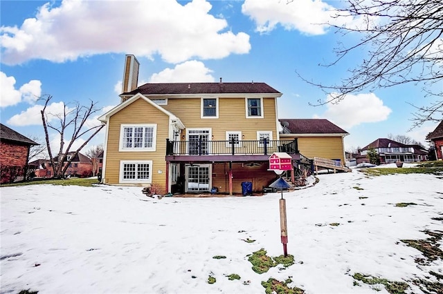 snow covered rear of property with a deck