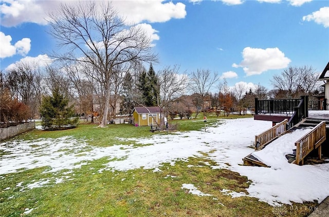 snowy yard featuring a shed and a deck