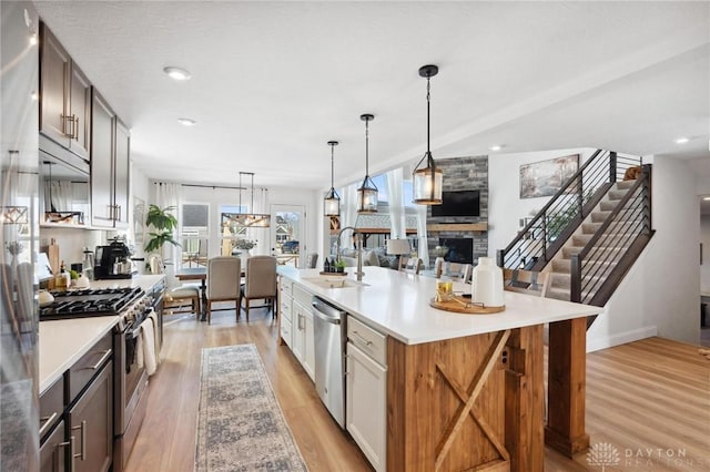 kitchen featuring light countertops, appliances with stainless steel finishes, hanging light fixtures, and a large island with sink