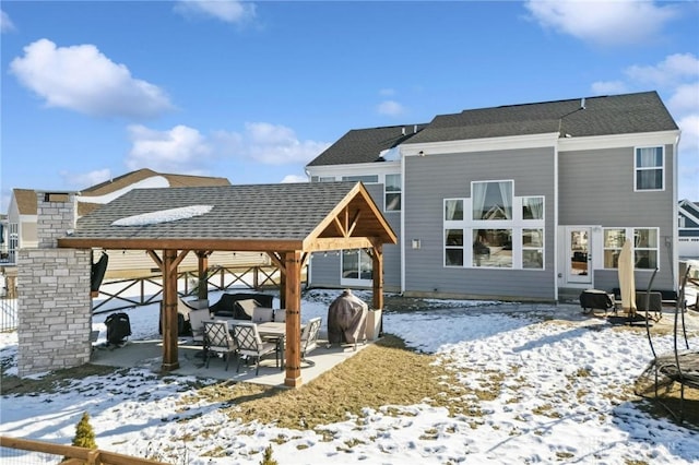 snow covered property with a gazebo and roof with shingles