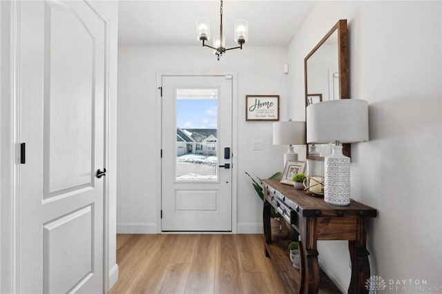 doorway to outside with an inviting chandelier and light hardwood / wood-style flooring