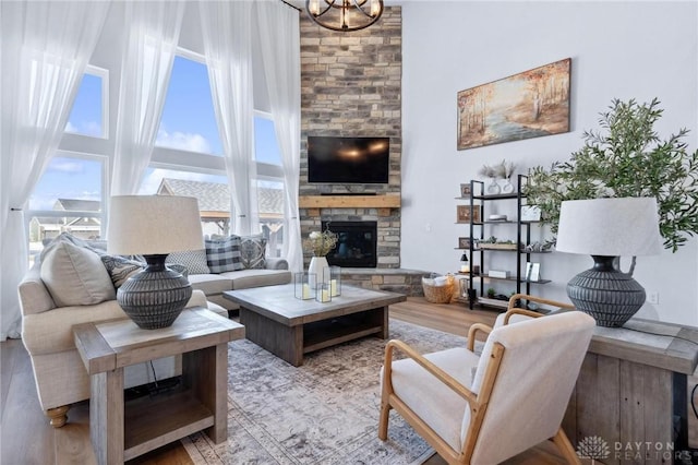 living room featuring a towering ceiling, a fireplace, and light hardwood / wood-style flooring