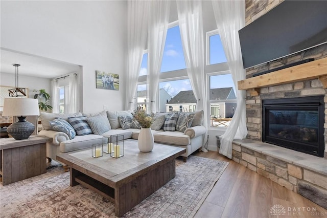 living area with a high ceiling, a fireplace, and wood finished floors