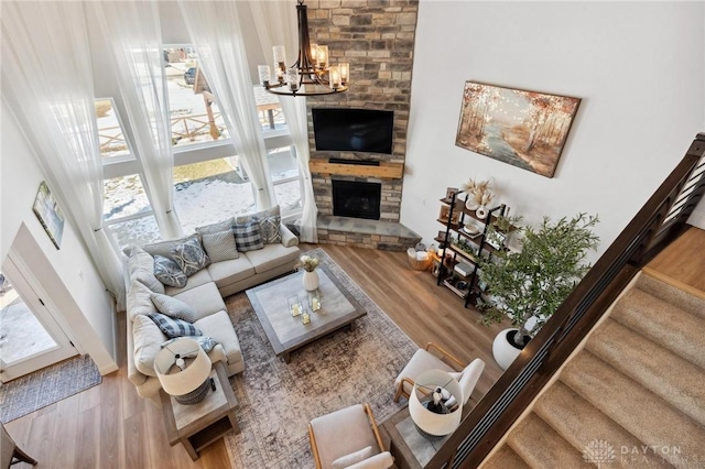 living area featuring a healthy amount of sunlight, a fireplace, stairway, and a chandelier