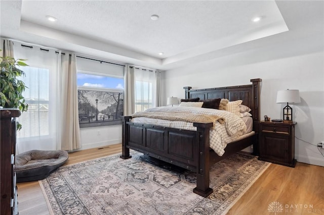 bedroom with a raised ceiling and light hardwood / wood-style flooring