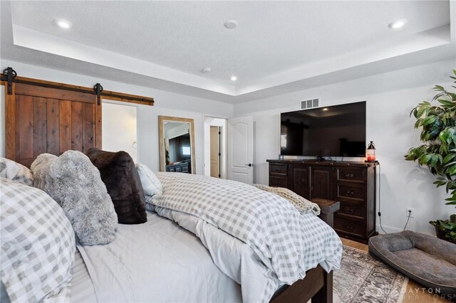 bedroom featuring a raised ceiling and a barn door