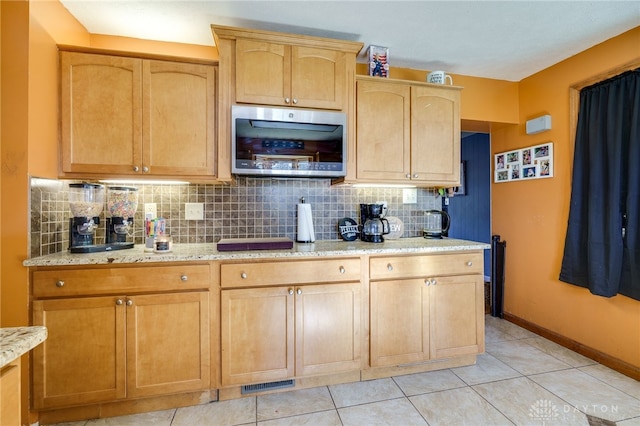 kitchen featuring light tile patterned flooring, light brown cabinetry, light stone countertops, and decorative backsplash