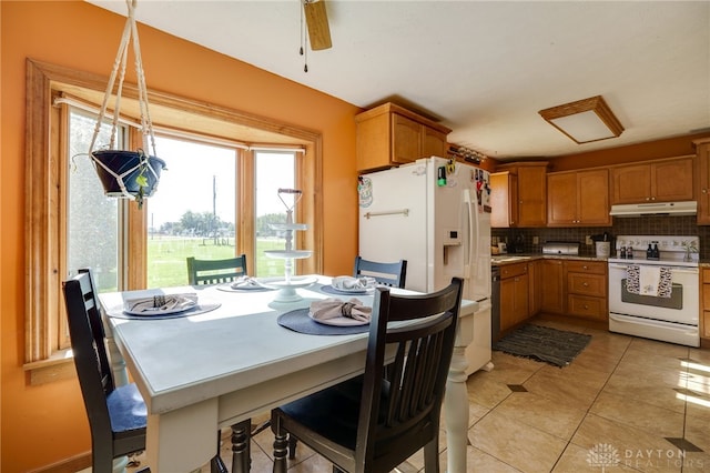 kitchen with hanging light fixtures, light tile patterned floors, backsplash, and white appliances