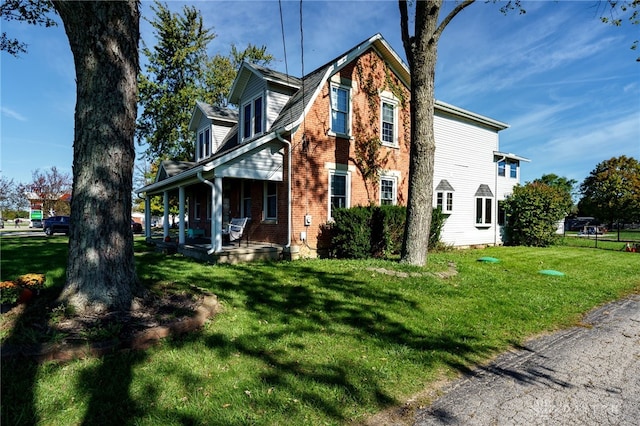 view of side of property featuring a porch and a lawn