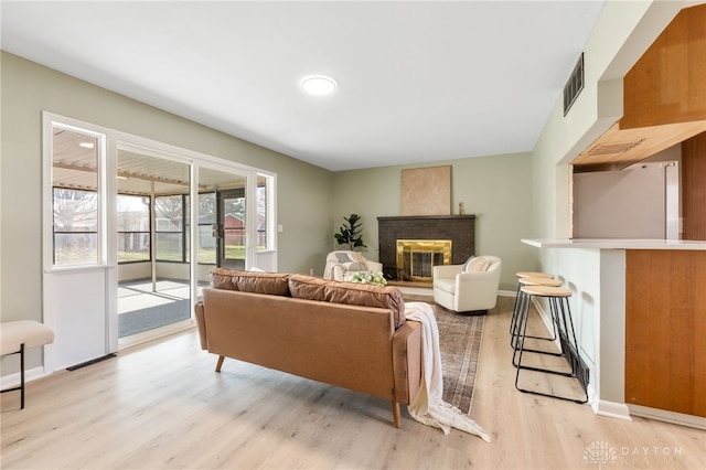 living room featuring a brick fireplace and light wood-type flooring