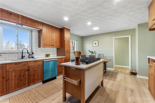 kitchen with sink, gas cooktop, light hardwood / wood-style floors, a kitchen island, and stainless steel dishwasher