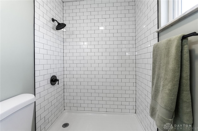 bathroom with a tile shower and toilet