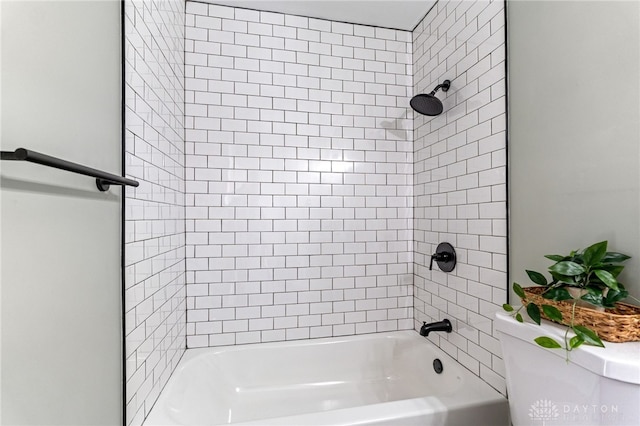 bathroom featuring tiled shower / bath combo and toilet