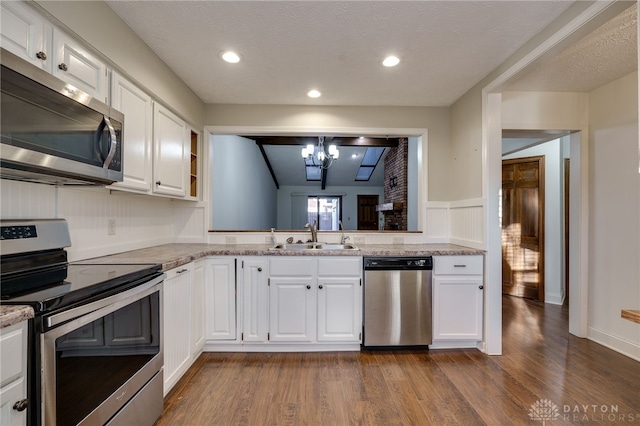 kitchen with dark wood-type flooring, sink, white cabinetry, appliances with stainless steel finishes, and light stone countertops