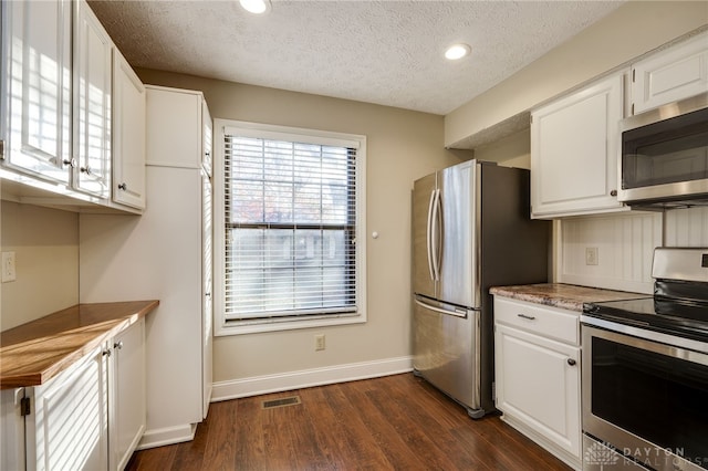 kitchen featuring white cabinetry, appliances with stainless steel finishes, dark wood-type flooring, and a textured ceiling