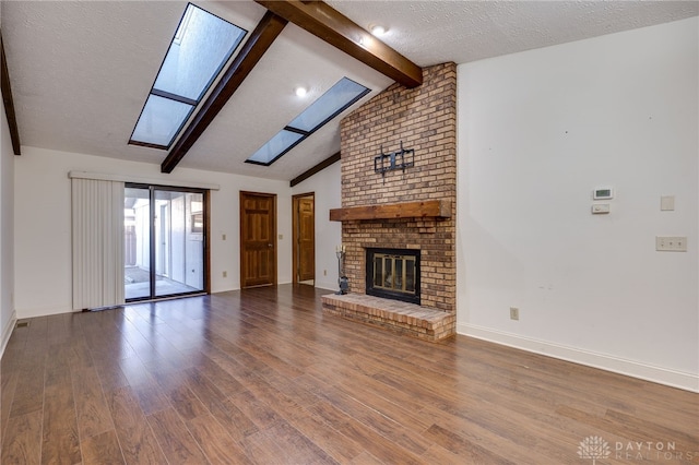 unfurnished living room featuring a textured ceiling, a fireplace, lofted ceiling with skylight, and wood-type flooring