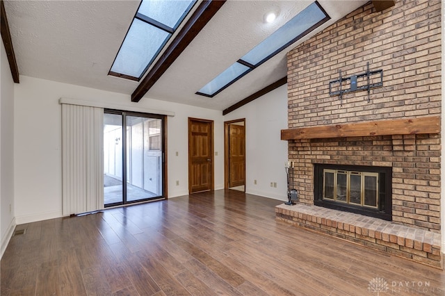 unfurnished living room with a fireplace, wood-type flooring, vaulted ceiling with skylight, and a textured ceiling