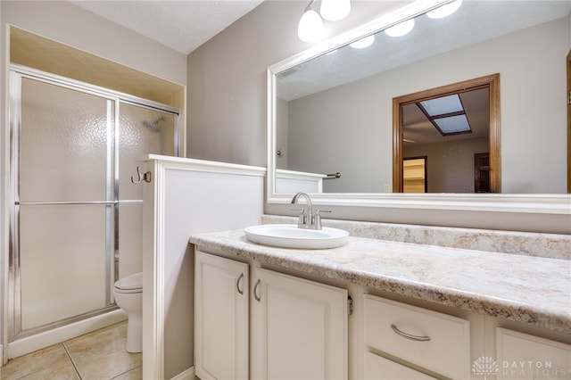 bathroom with tile patterned flooring, vanity, an enclosed shower, a textured ceiling, and toilet