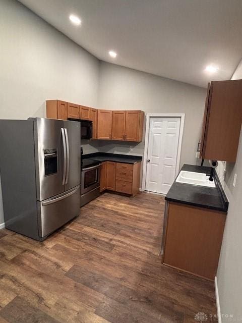 kitchen with vaulted ceiling, appliances with stainless steel finishes, dark wood-type flooring, and sink