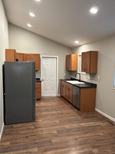 kitchen featuring vaulted ceiling, appliances with stainless steel finishes, sink, and dark hardwood / wood-style floors