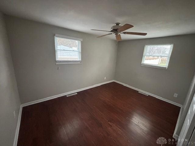 empty room with dark hardwood / wood-style flooring, ceiling fan, and a healthy amount of sunlight