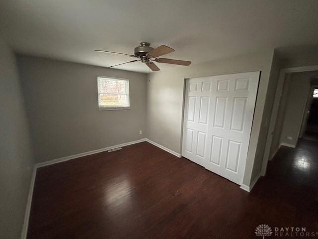 unfurnished bedroom featuring dark wood-type flooring, ceiling fan, and a closet