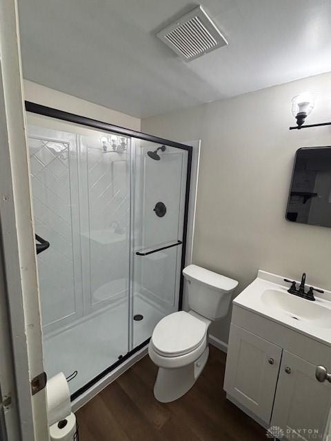 bathroom featuring hardwood / wood-style flooring, vanity, toilet, and a shower with shower door