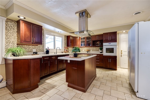 kitchen with backsplash, island exhaust hood, a center island, crown molding, and white appliances