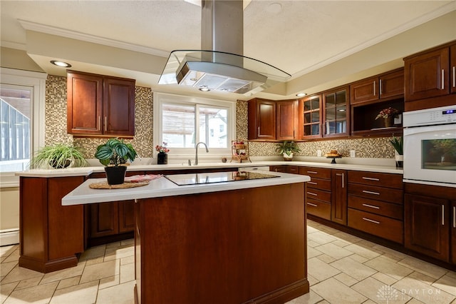 kitchen featuring crown molding, island exhaust hood, a center island, and white oven