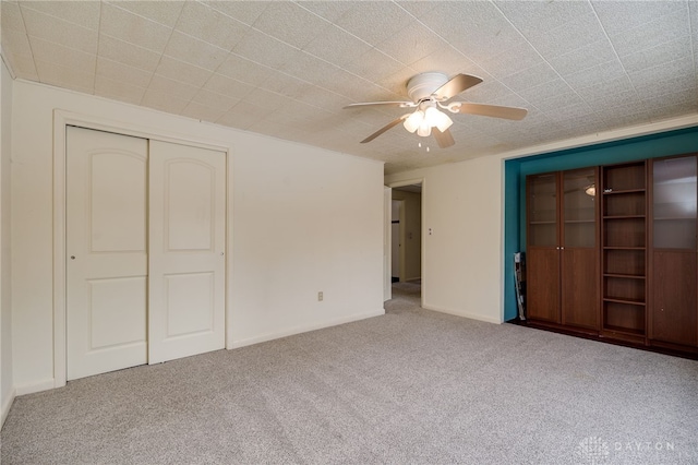 unfurnished bedroom featuring carpet flooring, ceiling fan, and a closet