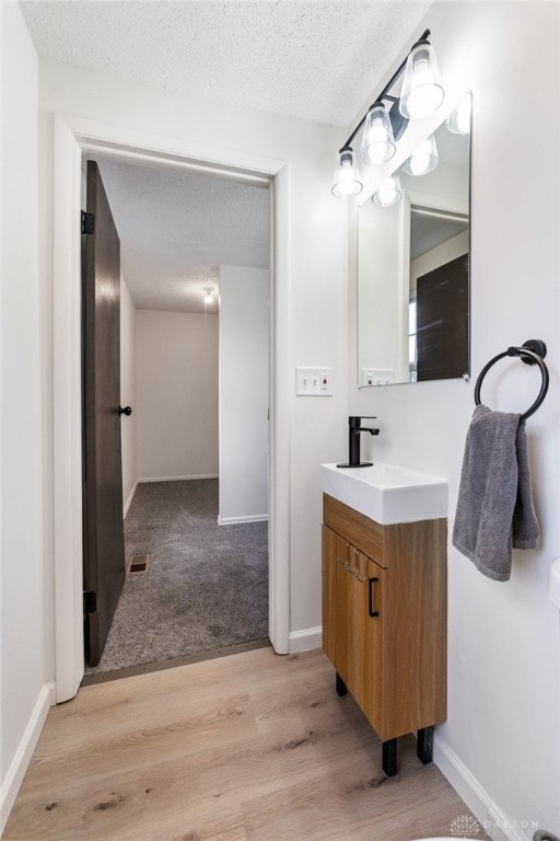 bathroom featuring hardwood / wood-style flooring, vanity, and a textured ceiling