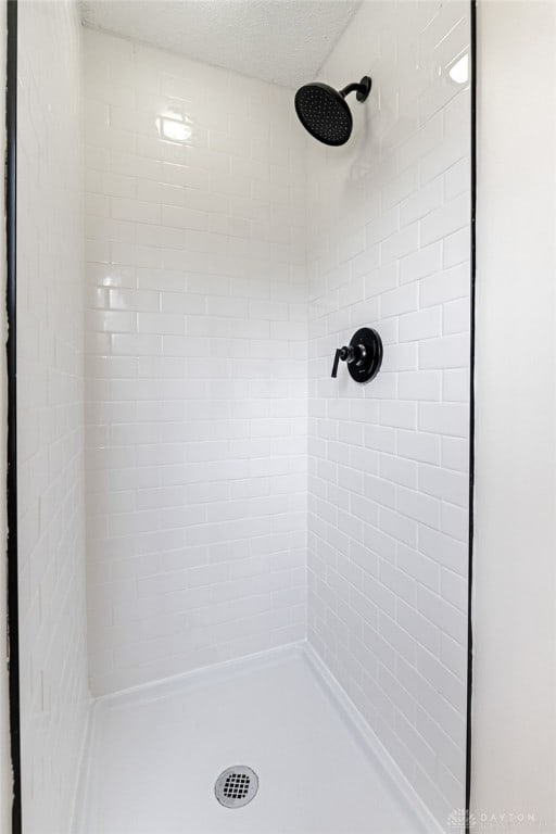 bathroom with tiled shower and a textured ceiling