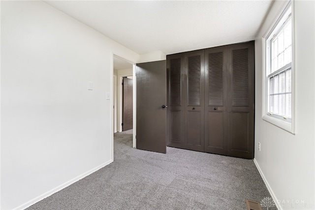 unfurnished bedroom featuring light colored carpet and a closet